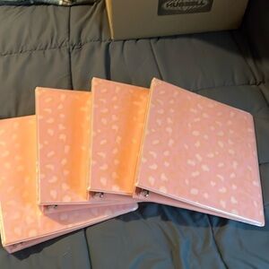 Four pink three ring binders